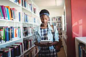 Attentive schoolgirl using digital tablet in library