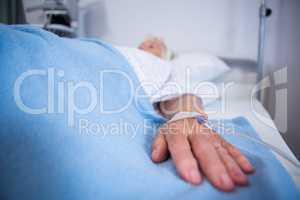 Senior patient hand with saline on bed in hospital