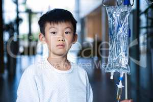 Boy patient holding intravenous iv drip stand in corridor