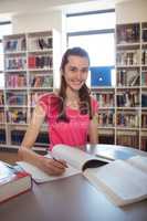 Schoolgirl doing homework in in library at school