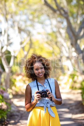 Smiling woman standing with digital camera