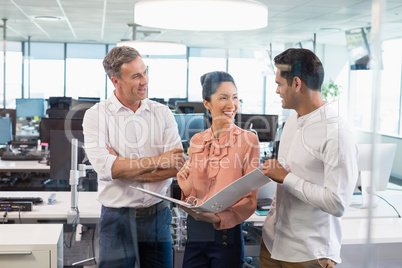 Smiling business colleagues discussing over clipboard at desk Smiling business colleagues discussing over clipboard at desk