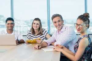 Portrait of smiling business colleagues with laptop in meeting