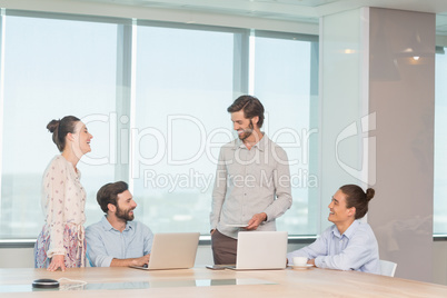 Smiling business executives discussing with each other in conference room