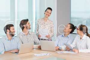 Smiling business executives interacting with each other in conference room