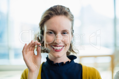 Smiling female business executive with headset sitting in office