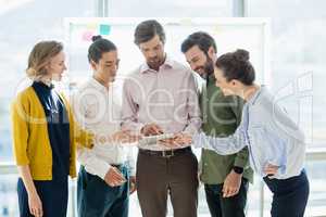 Smiling business executives discussing over digital tablet