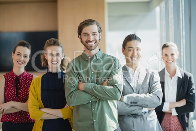 Business executives with arms crossed smiling while standing in office