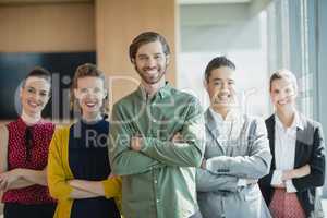 Business executives with arms crossed smiling while standing in office