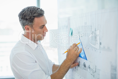 Architect drawing on blueprint at whiteboard
