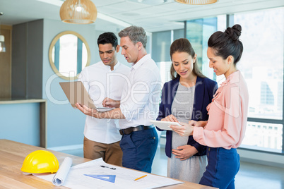 Architects discussing over laptop and digital tablet in conference room