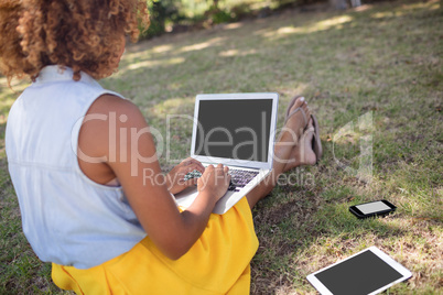 Woman sitting in park and using laptop