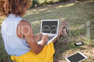 Woman sitting in park and using laptop