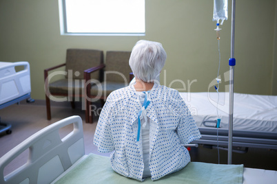 Rear-view of senior patient sitting on bed