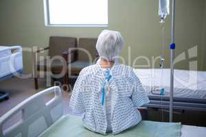 Rear-view of senior patient sitting on bed
