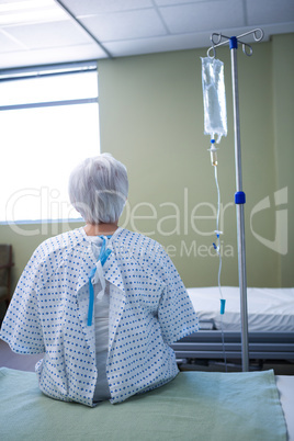 Rear-view of senior patient sitting on bed