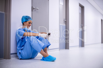 Surgeon sitting on floor and using mobile phone