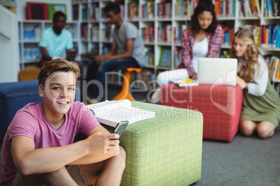 Student holding mobile phone in library