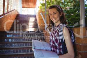 Portrait of schoolgirl reading book near staircase