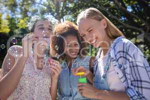 Female friends blowing bubble in park