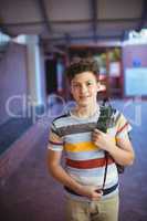 Happy schoolboy standing in school campus