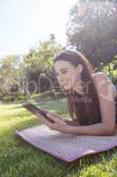 Smiling woman lying on mat and using digital tablet