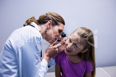 Female doctor examining patient ear with otoscope