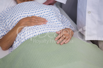 Mid-section of doctor consoling senior patient