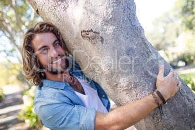Portrait of man hugging a tree trunk in park