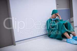 Tensed female surgeon sitting in corridor