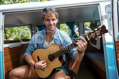 Man playing guitar in campervan