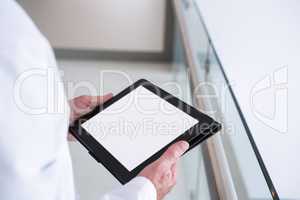 Doctor using a digital tablet in the passageway at hospital