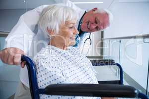 Doctor holding senior patient on wheelchair in passageway