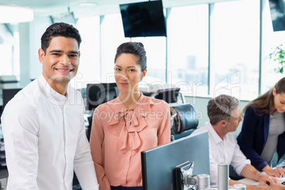 Portrait of smiling business colleagues standing together at desk