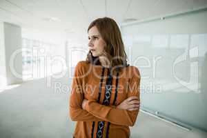 Business executive standing with arms crossed in office corridor