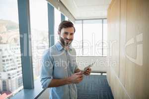 Portrait of smiling business executive using digital tablet in corridor