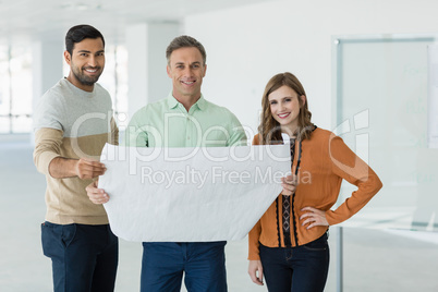 Portrait of smiling business colleagues discussing over blueprint
