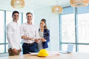Smiling architects discussing over digital tablet in conference room