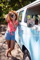 Woman leaning on campervan and photographing with camera