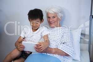Senior patient and boy holding digital tablet