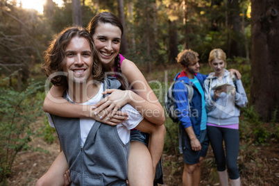 Portrait of a man giving a piggy back to the woman while hiking