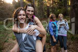 Portrait of a man giving a piggy back to the woman while hiking