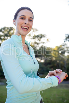 Portrait of smiling female jogger checking her fitness band