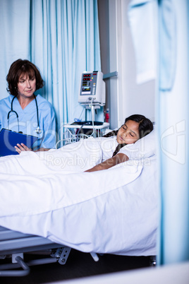 Doctor writing on clipboard while looking at patient