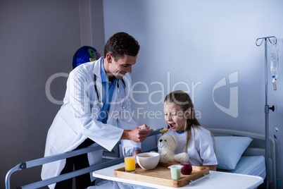 Doctor feeding breakfast to patient