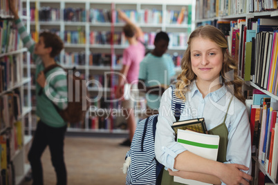 Portrait of happy schoolgirl holding books in library