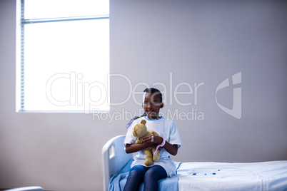 Patient sitting on the bed with teddy bear at hospital