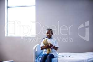 Patient sitting on the bed with teddy bear at hospital