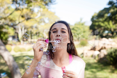 Woman blowing bubbles in park