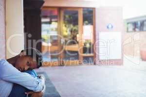 Sad schoolgirl sitting in school campus